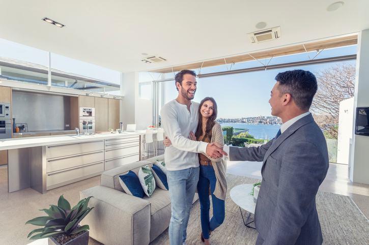 Real estate agent with couple in luxury home.