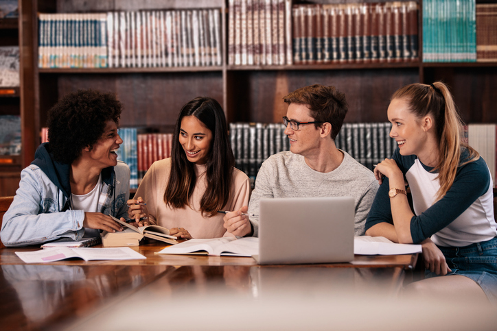 Happy students working on college project in library