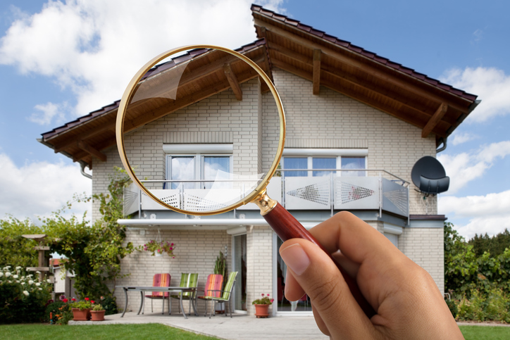 Close-up Of Person's Hand Holding Magnifying Glass Over Luxury House Outdoors