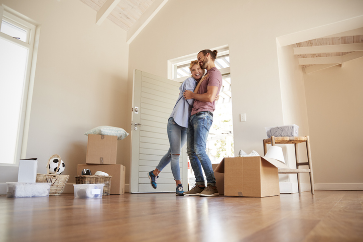 Happy Couple Surrounded By Boxes In New Home On Moving Day