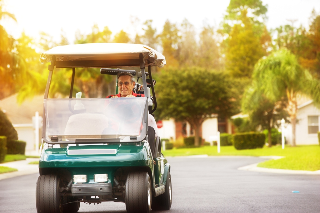 An elder man driving a club car