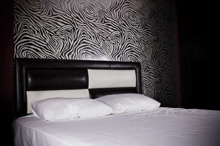 Bedroom decorated with zebra wallpaper and black and white bed headboard